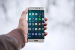 Hand holding an Android smartphone showing apps