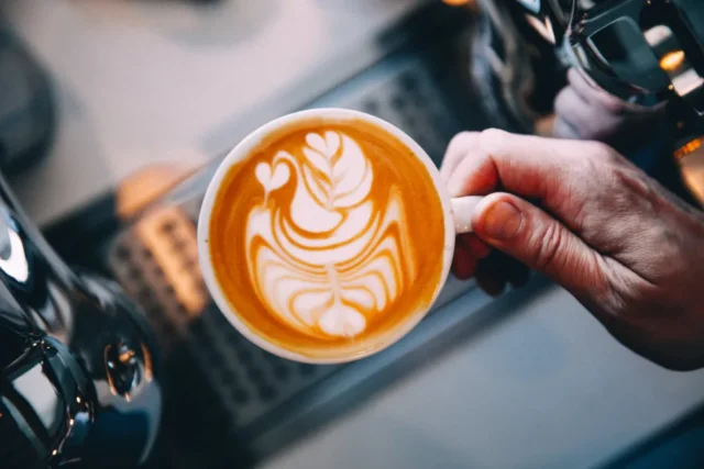 Cup of coffee beside a laptop and smartphone on a desk in the morning