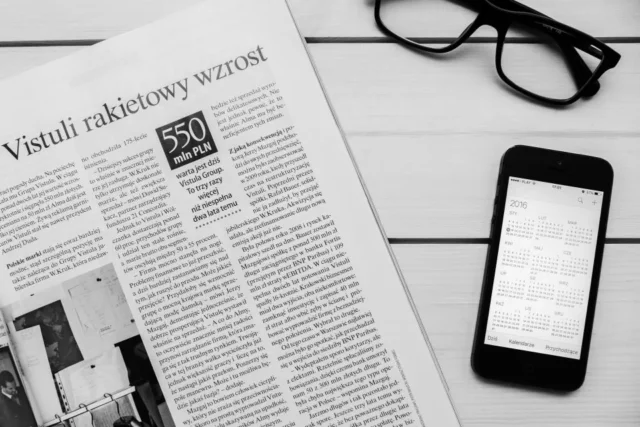 Smartphone and glasses resting on a newspaper
